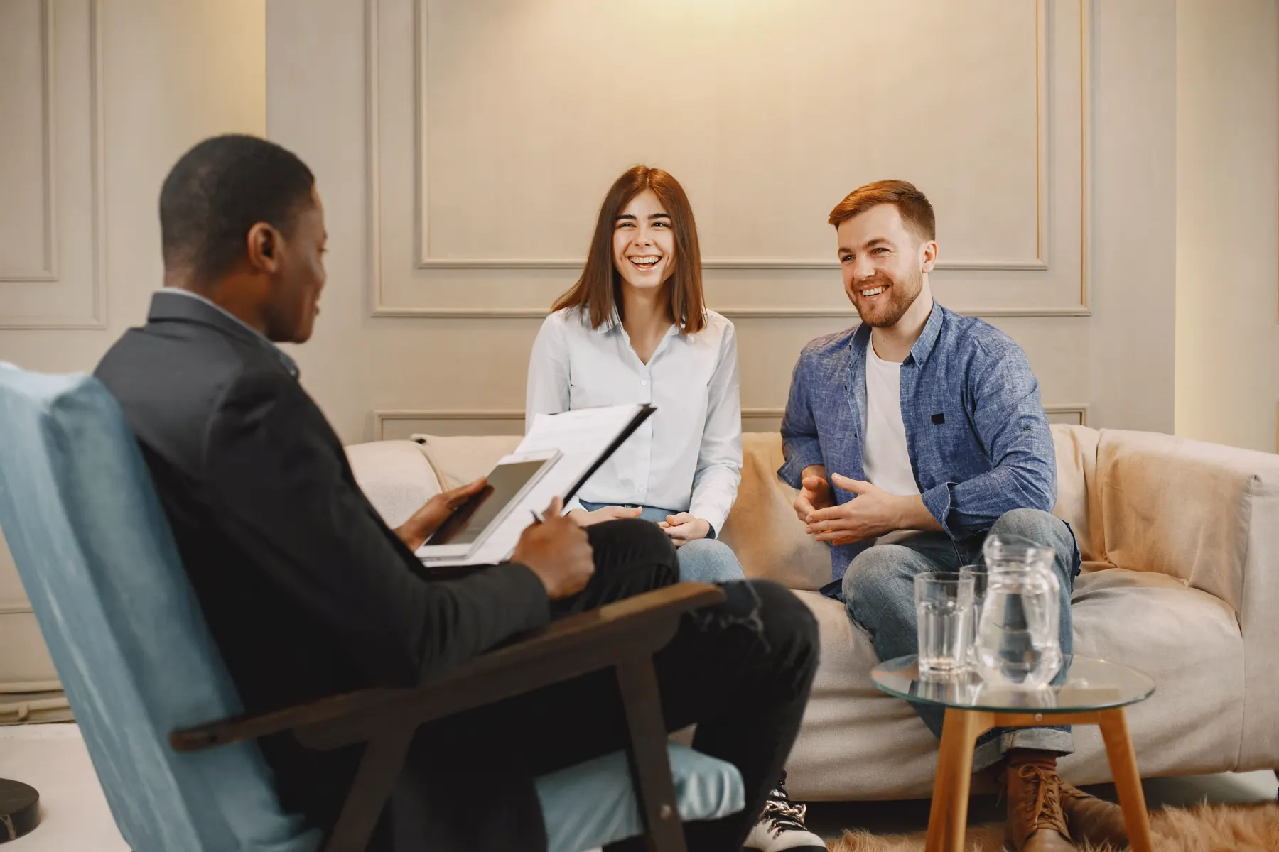 A couple smiling with an advisor in their living room