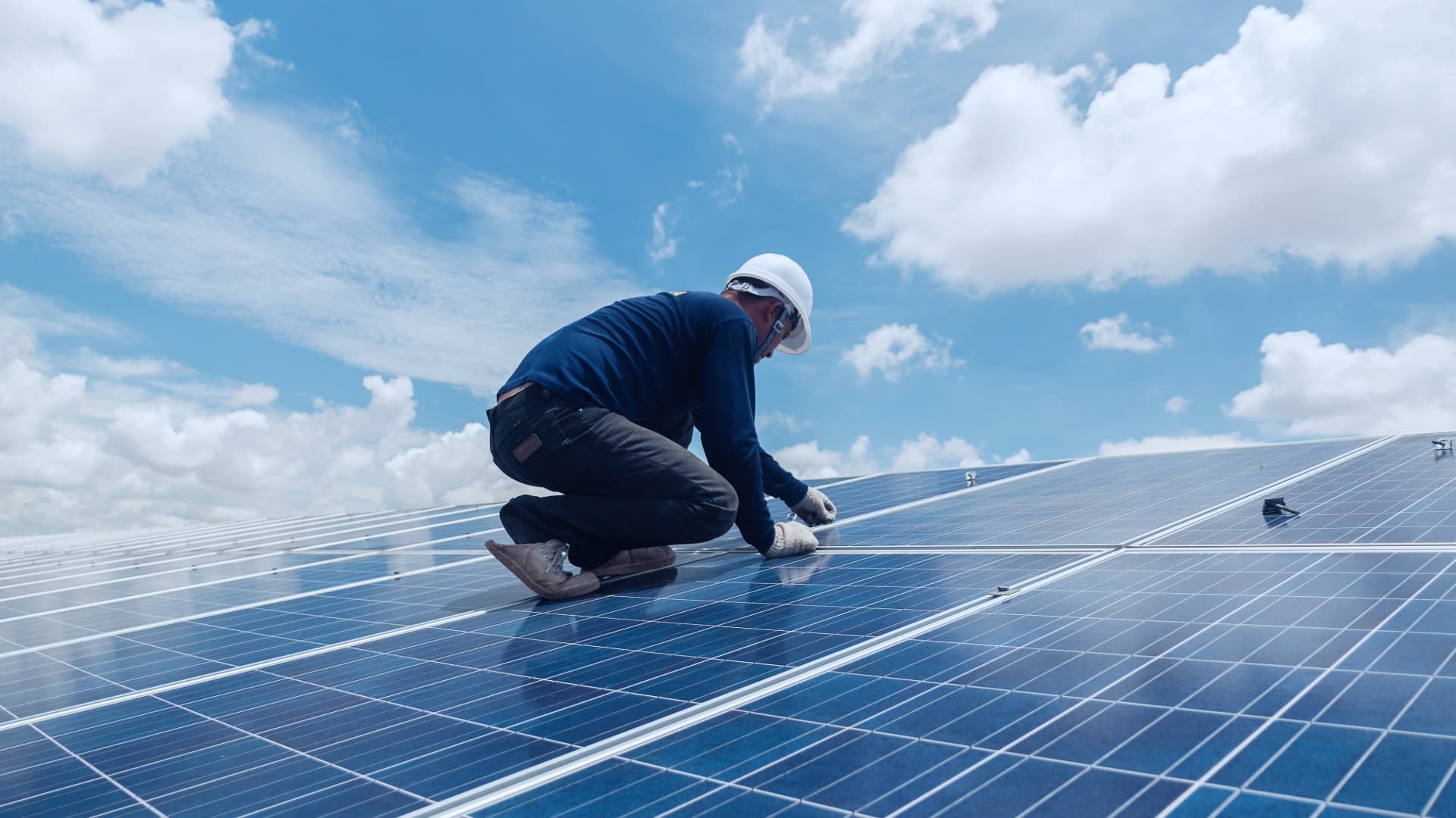 Technician installing panels on a large commercial solar array